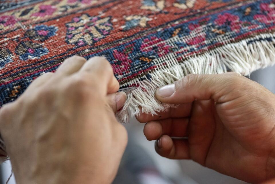 Securing a rug's fringe and end knots by hand with a needle